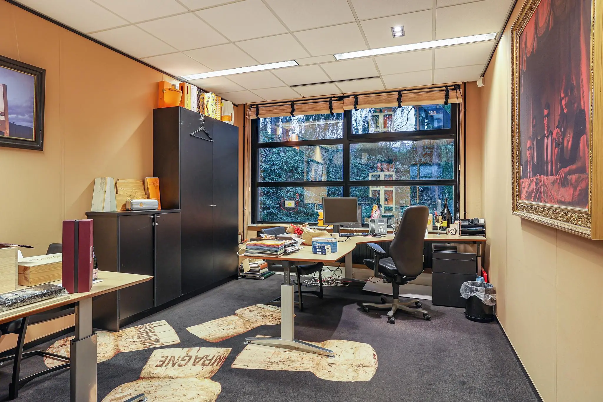 Kantoorruimte aan de Oude Utrechtseweg met bureau, stoelen, kasten en groot raam met uitzicht op een tuin.